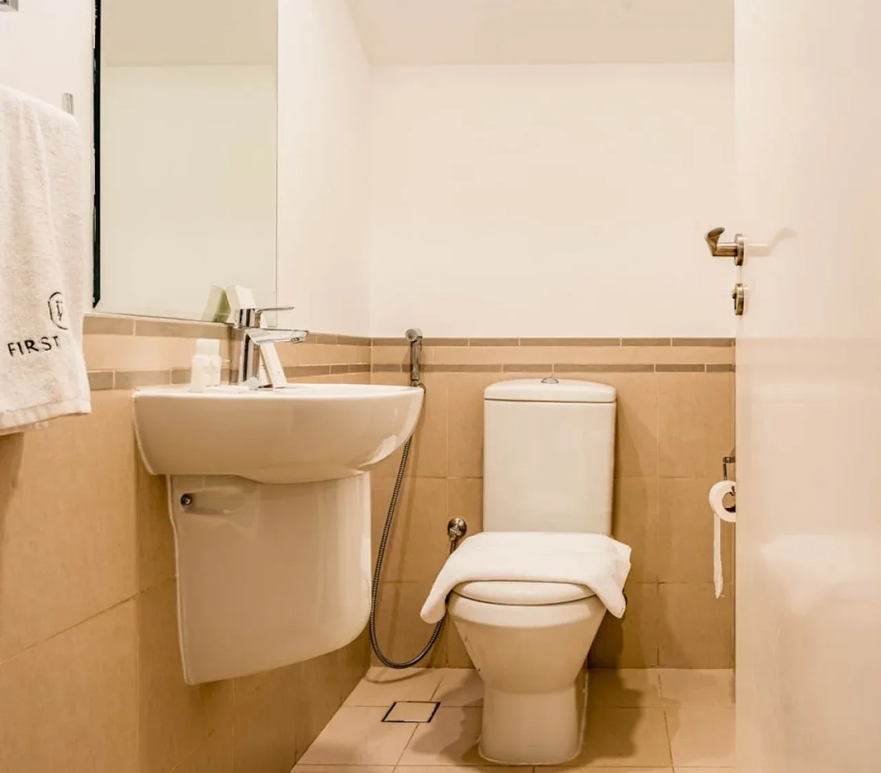 A bathroom with a sink and toilet against tiled walls.