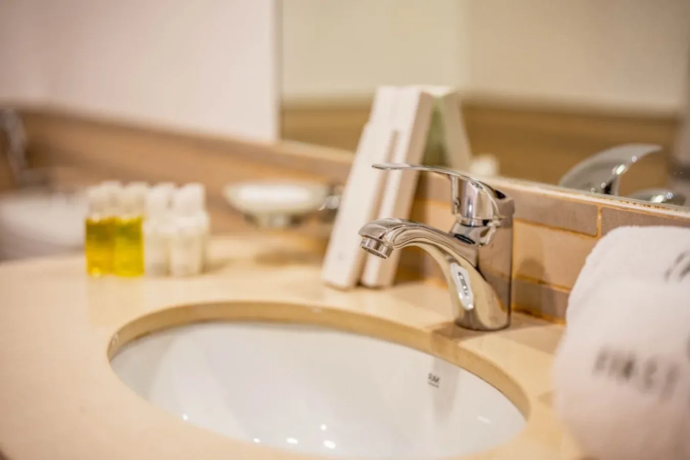 A bathroom sink with a chrome faucet and toiletries on the counter.