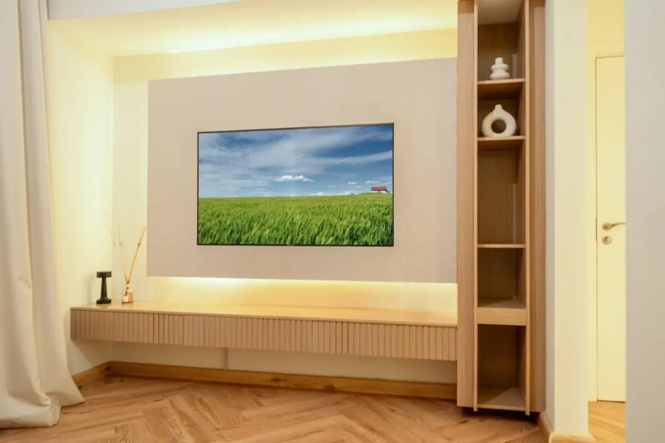 A bright living room features a wall-mounted television above a low wooden console.