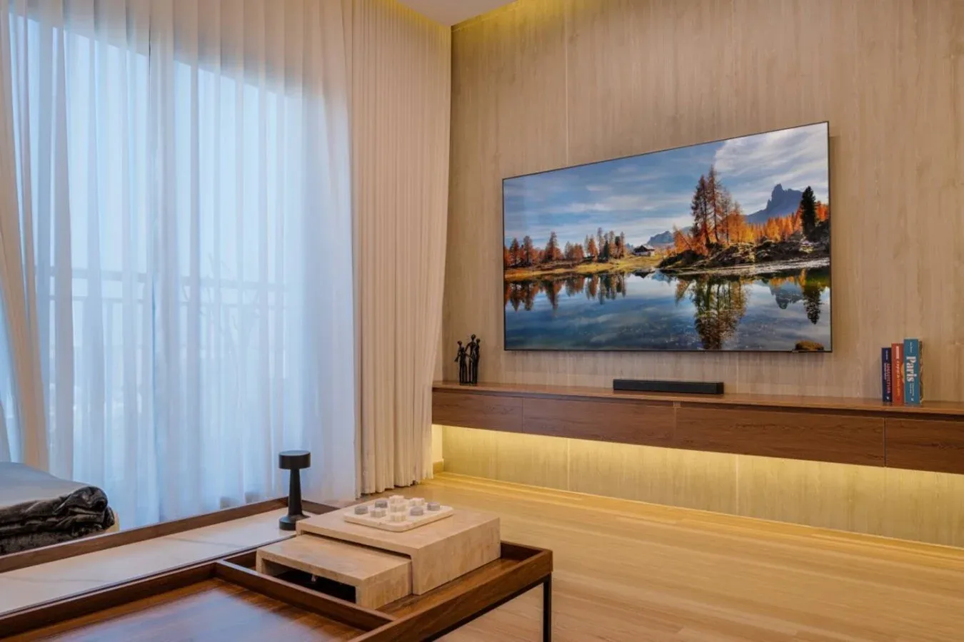 A living room with a wall-mounted television above a wooden media console.