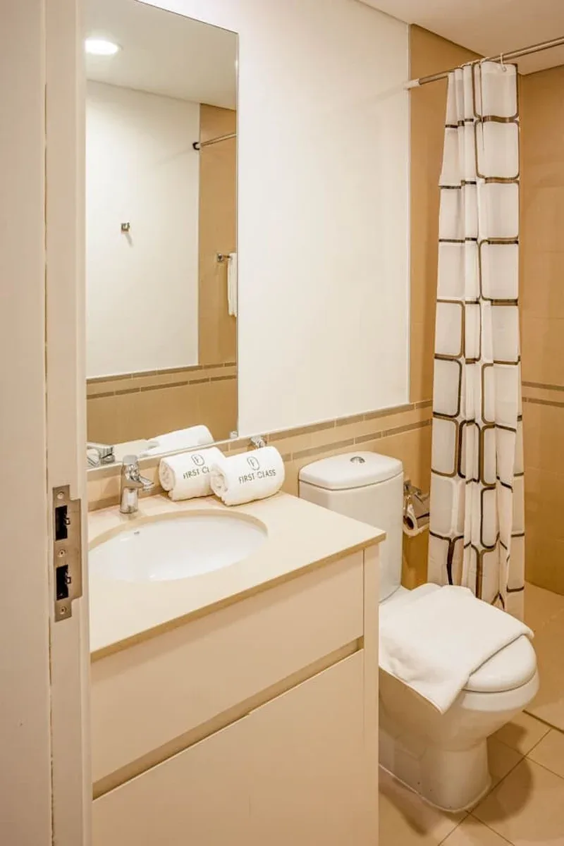 A bathroom with a sink, mirror, toilet, and shower curtain.