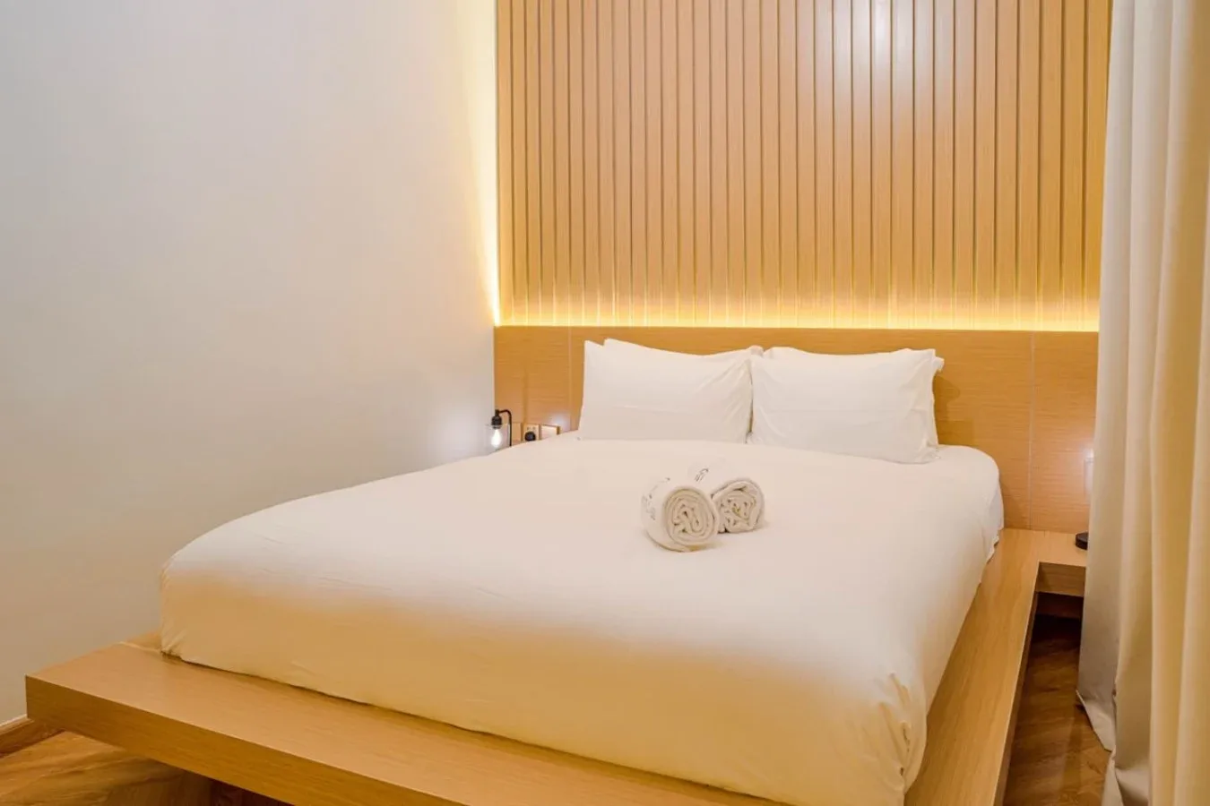 A bedroom with a neatly made bed and a wood-paneled wall.