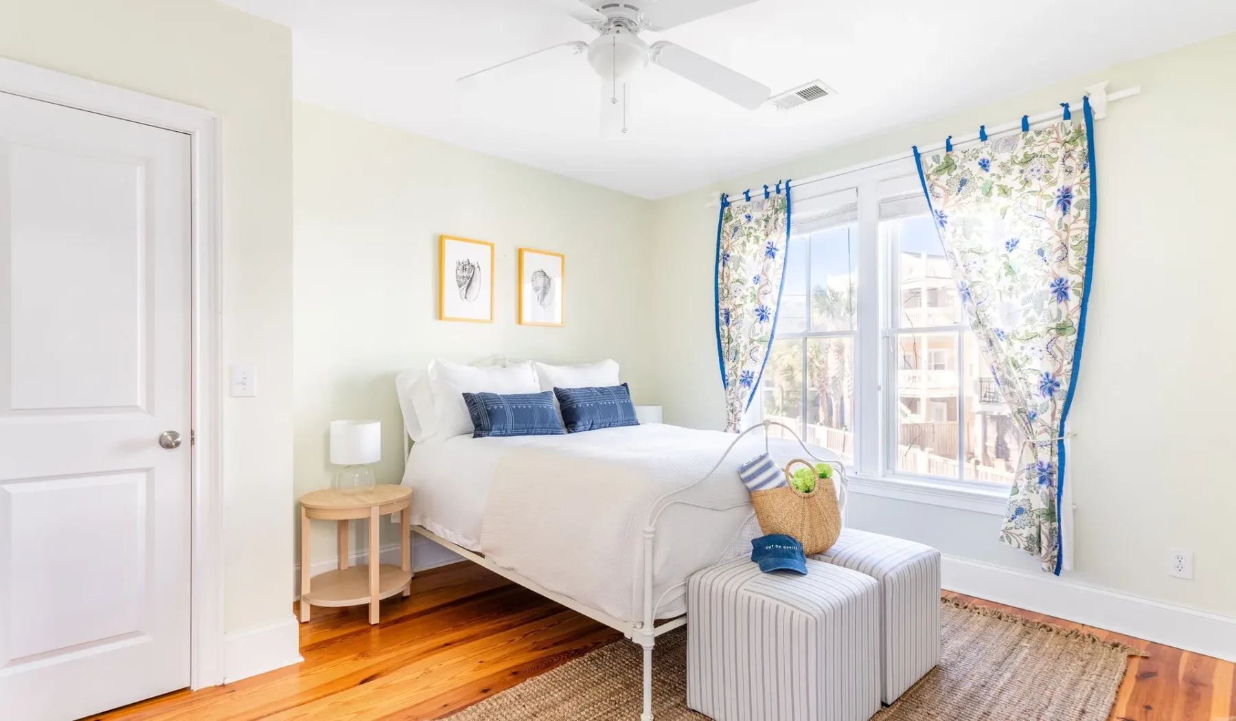 A bright bedroom with a white bed beside a large window.