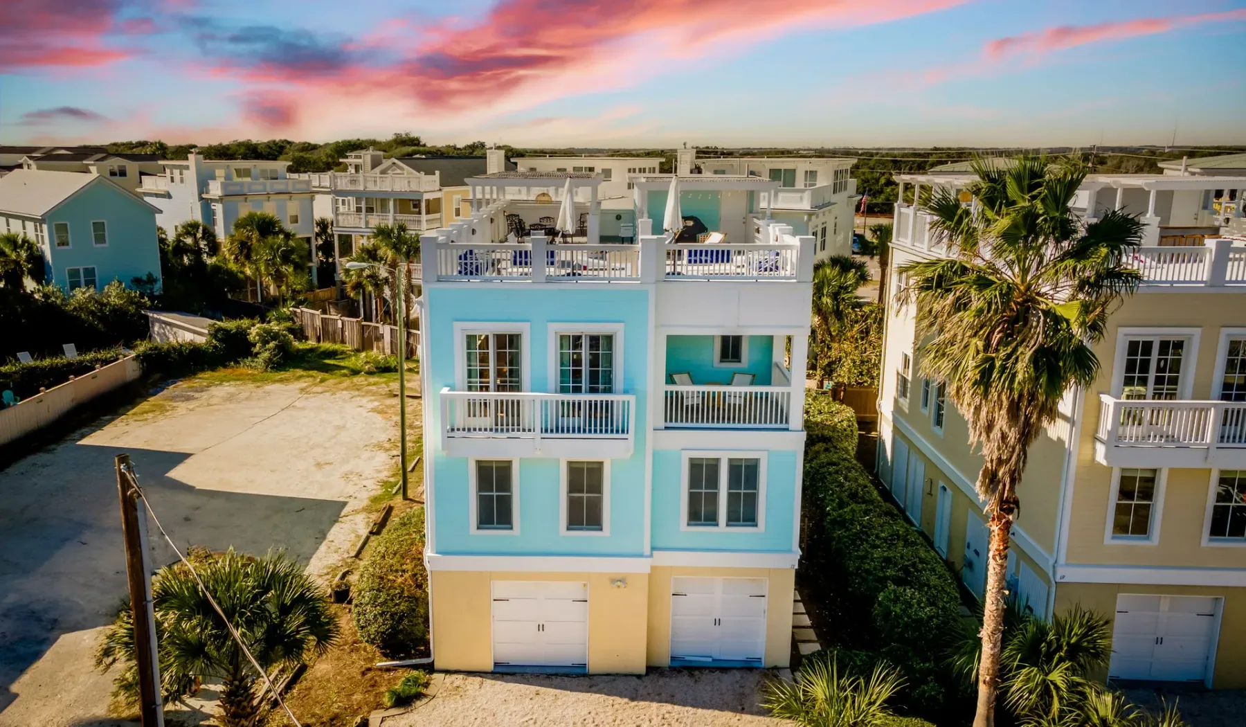 Aerial view of colorful coastal houses beneath a pink and blue sky.