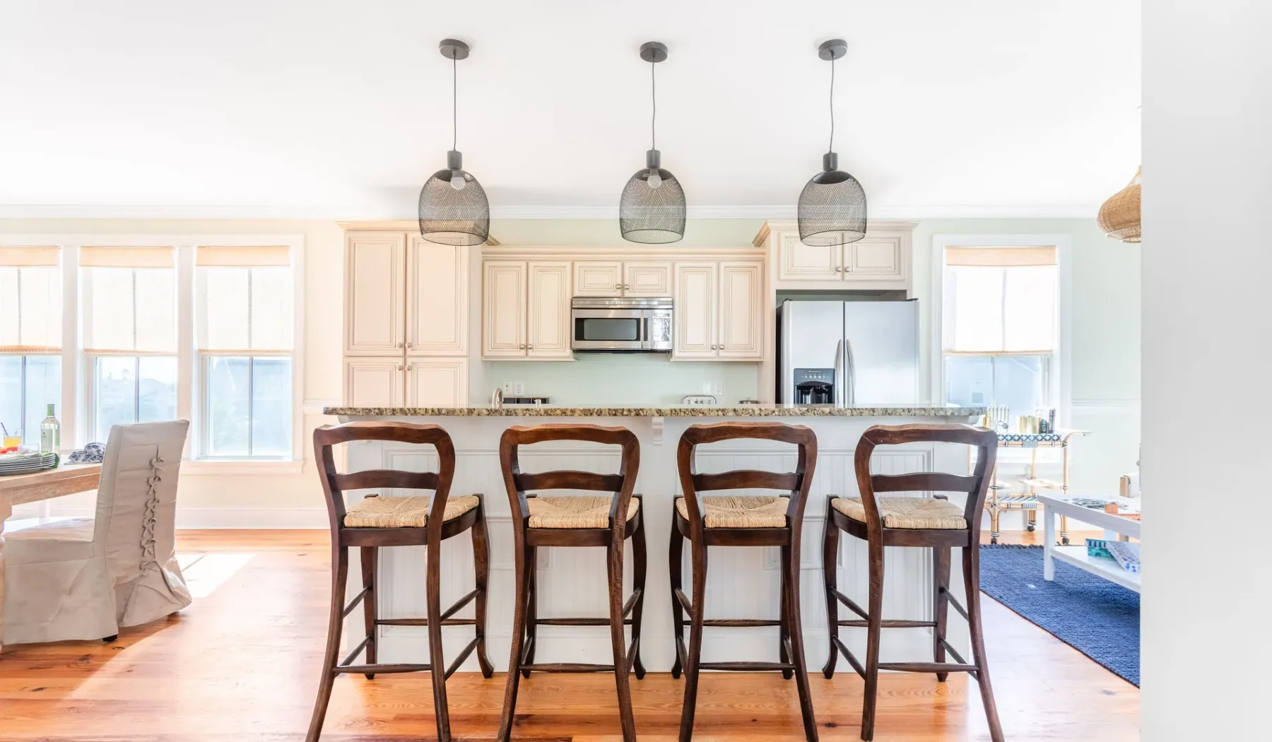 A bright kitchen and dining area with a counter, bar seating, and pendant lights.