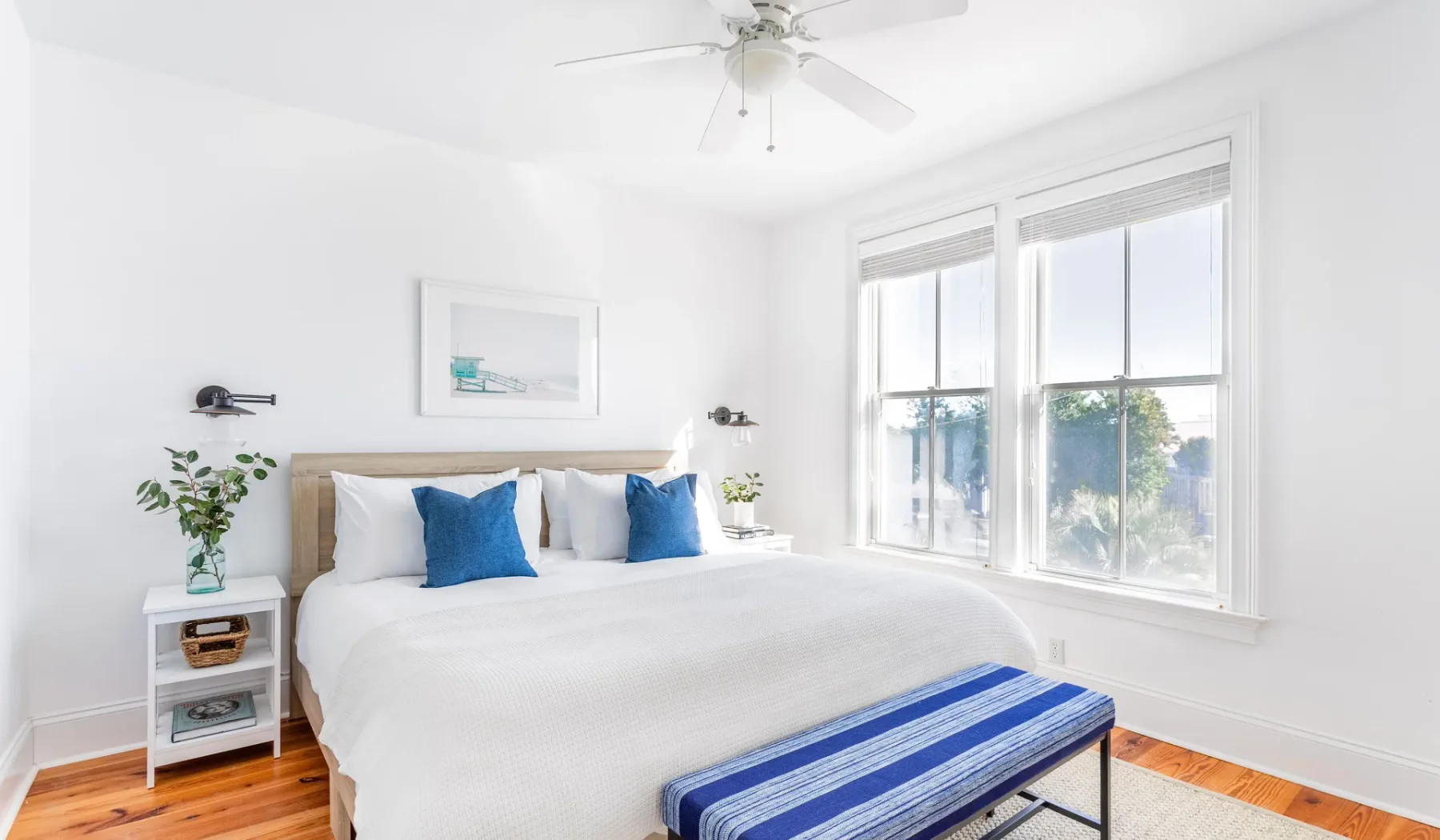 A bright bedroom with a neatly made bed and large windows.