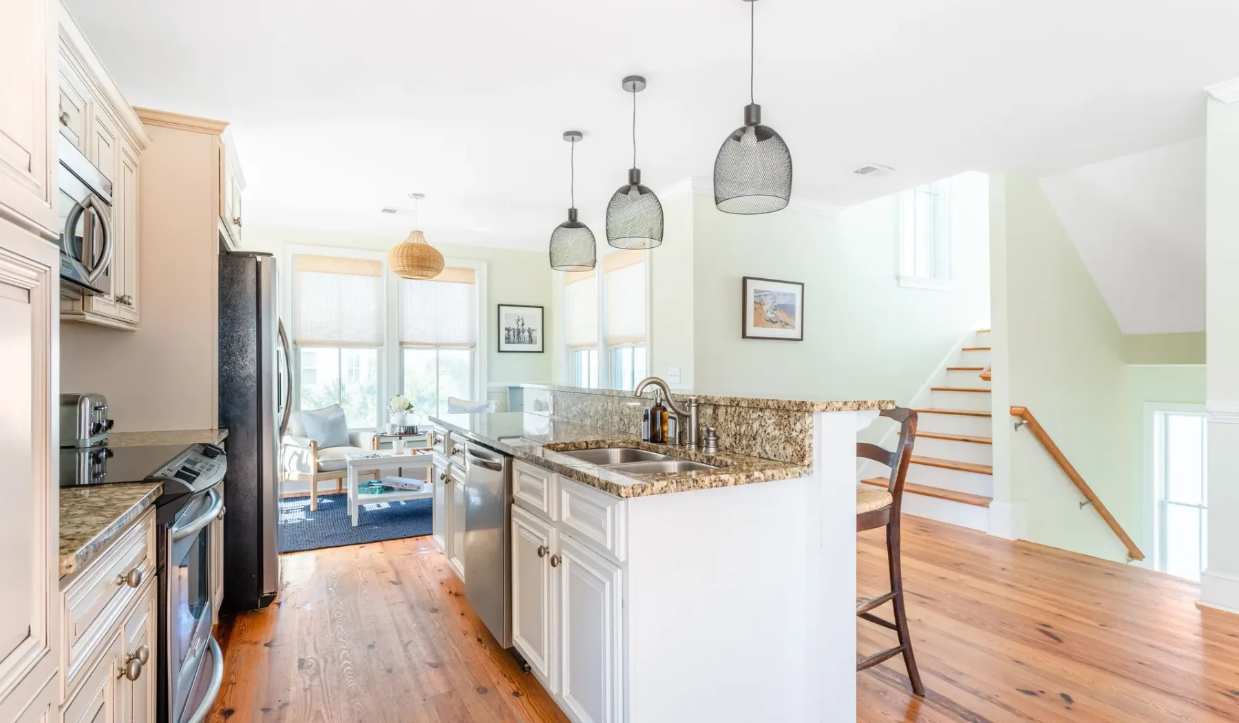 A bright kitchen with a central island and pendant lights.