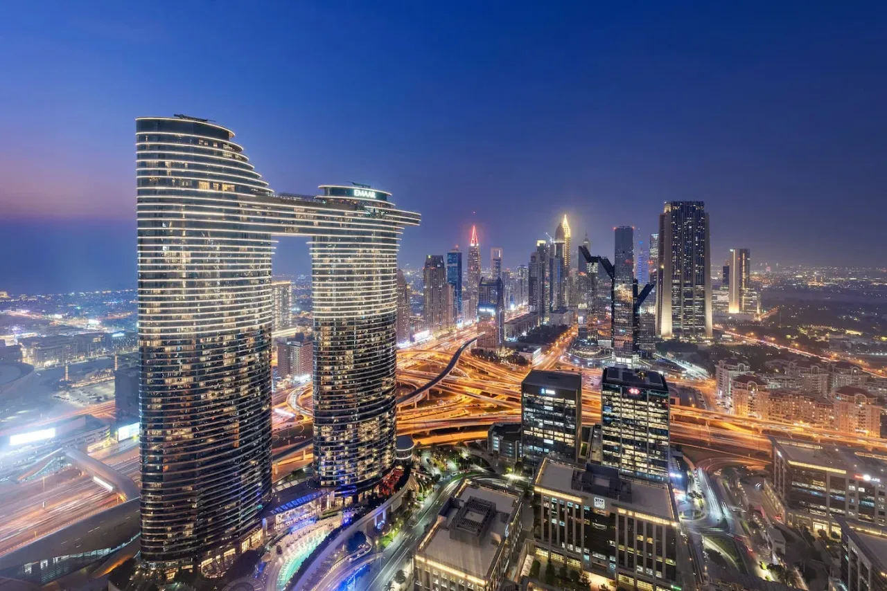 Un horizonte urbano al anochecer, con edificios altos iluminados y carreteras.