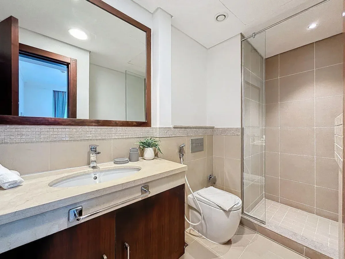 Un baño con un amplio lavabo, espejo de pared y ducha de vidrio.