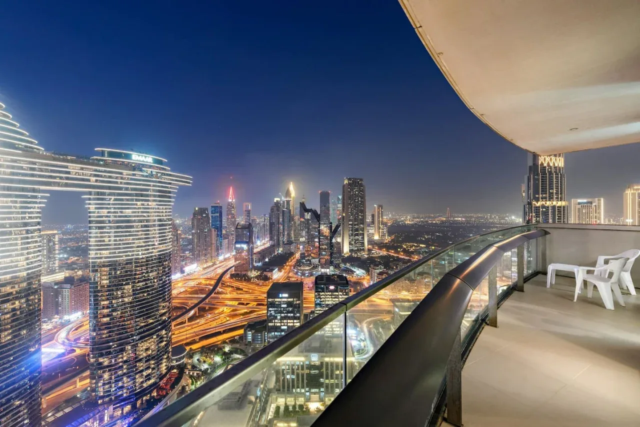 Un balcón ofrece vistas de un horizonte urbano iluminado por la noche.
