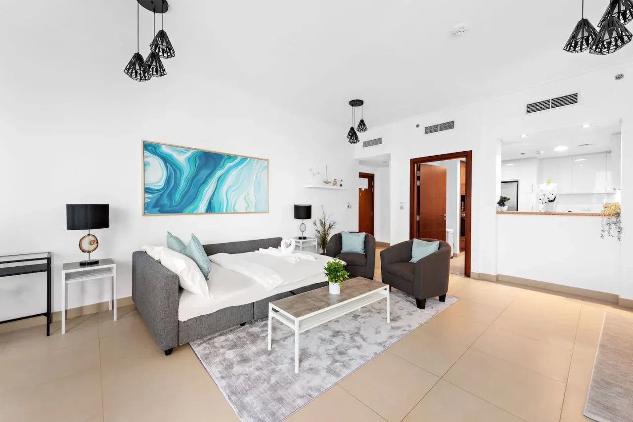 Una sala luminosa con asientos, una mesa de centro y una cocina abierta.
