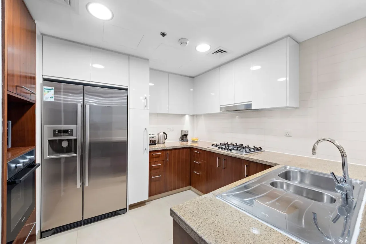Una cocina moderna con gabinetes de madera, electrodomésticos de acero inoxidable y un fregadero grande.