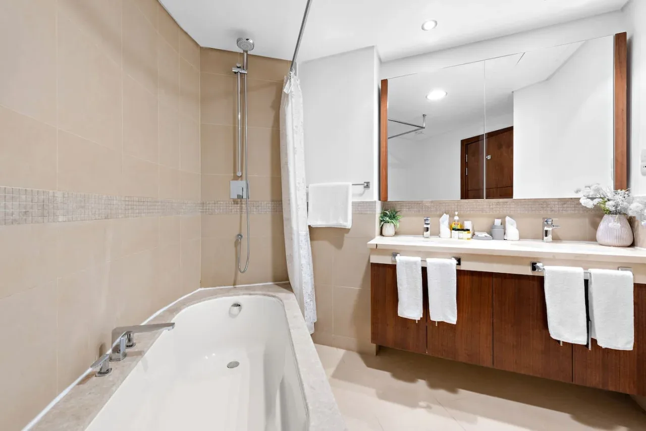 Un baño luminoso con bañera, ducha y un amplio tocador.