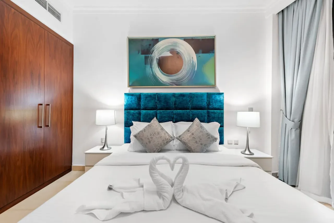 Un dormitorio con una cama bien arreglada, cabecero turquesa y arte abstracto.
