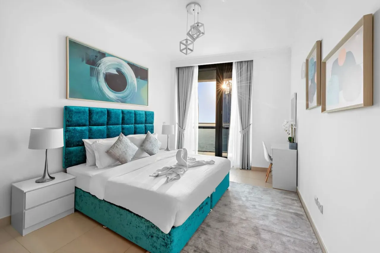 Un dormitorio con una cama, un cabecero turquesa y cortinas junto a la ventana.