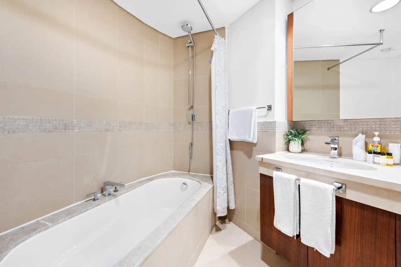 Un baño con bañera, cortina de ducha y lavabo con mueble.