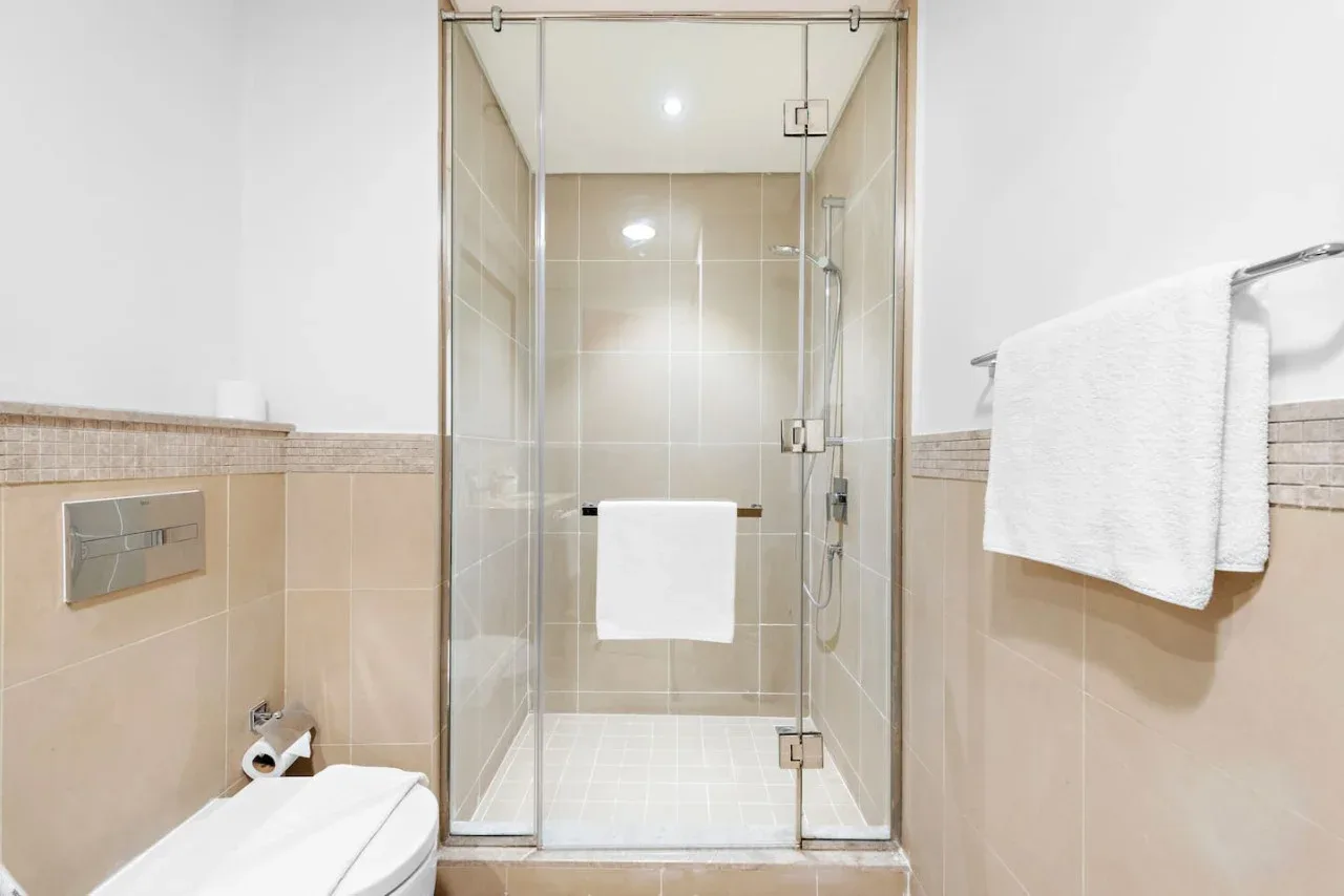 Un baño con una ducha de vidrio y una toalla colgada en la pared.