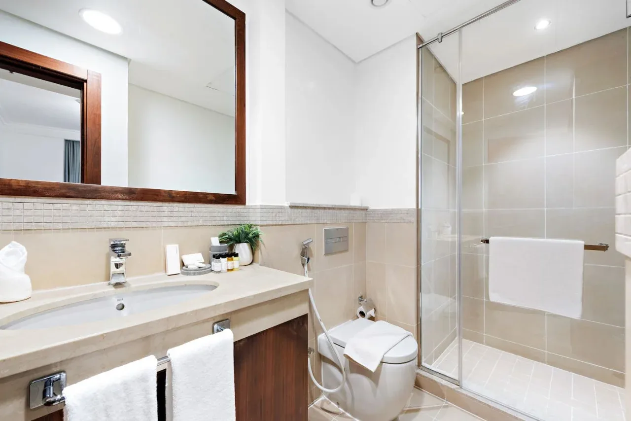 Un baño con lavabo, espejo, inodoro y ducha de cristal.