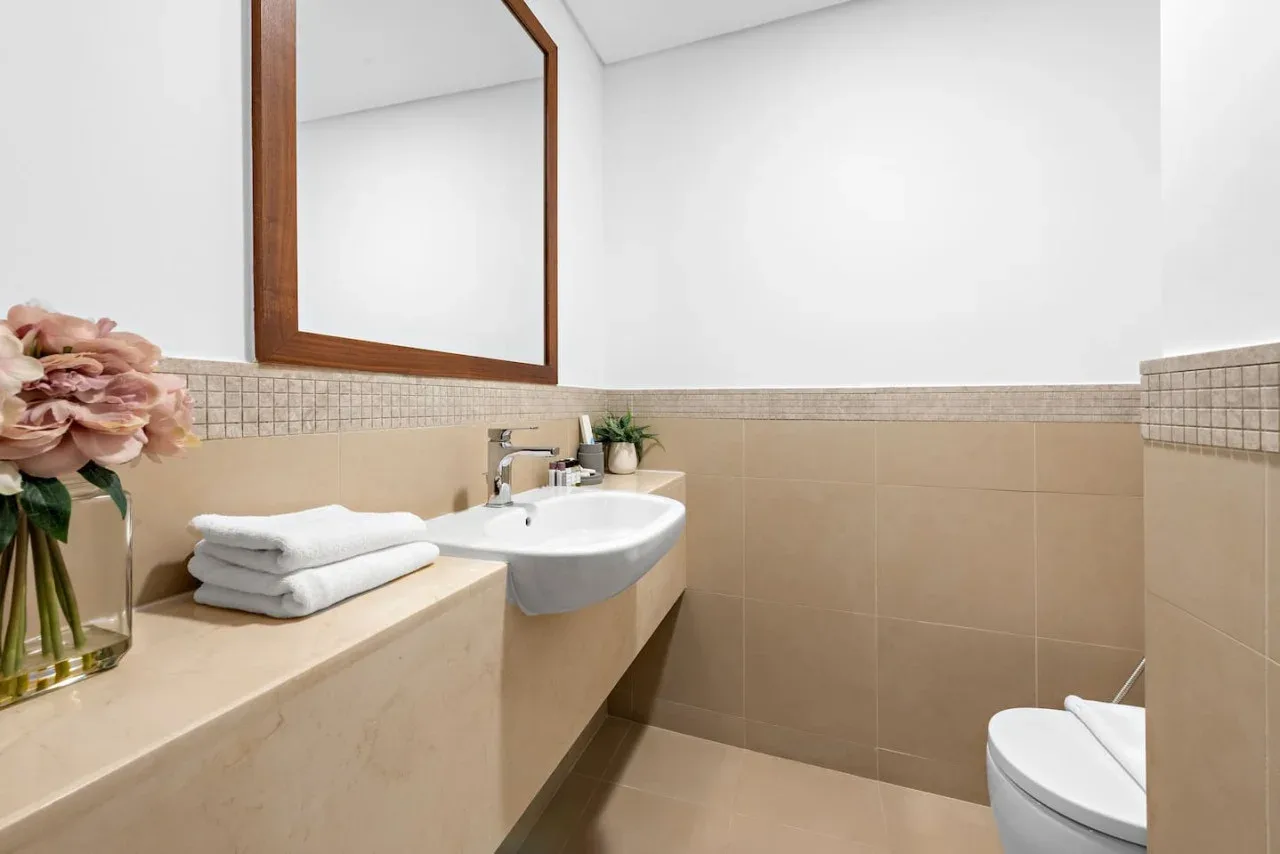Un baño con lavabo, espejo y toallas dobladas sobre la encimera.