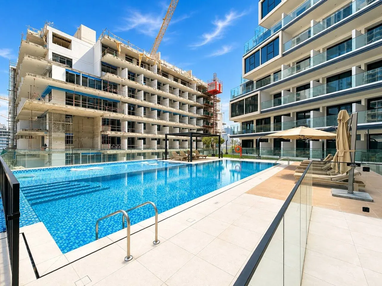 Una piscina al aire libre se encuentra entre edificios modernos bajo un cielo despejado.