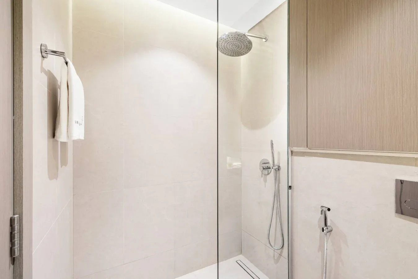 Un baño luminoso con una ducha de cristal y un cabezal fijado a la pared.