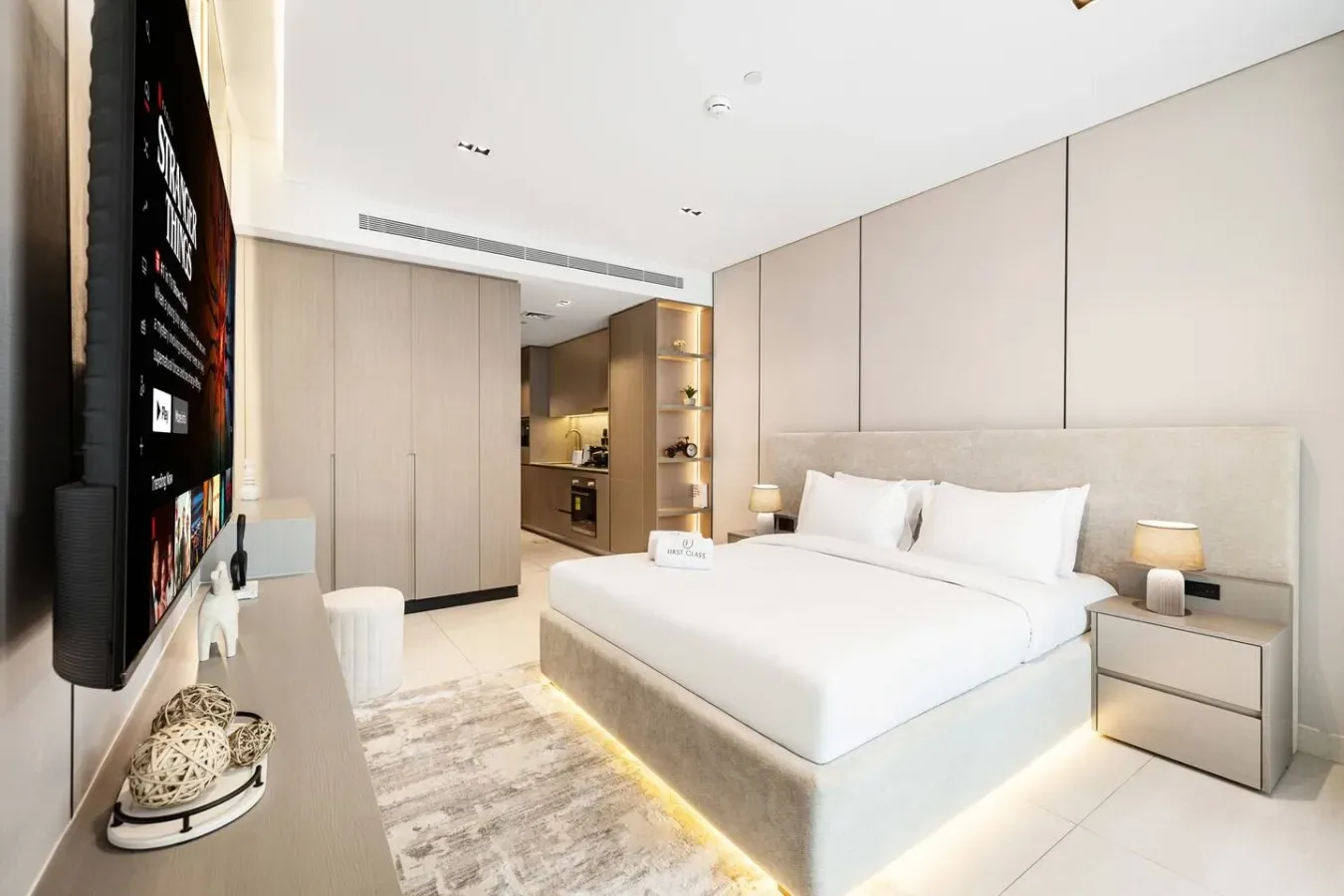 Un dormitorio moderno con una cama grande, mesas de noche y un televisor montado en la pared.