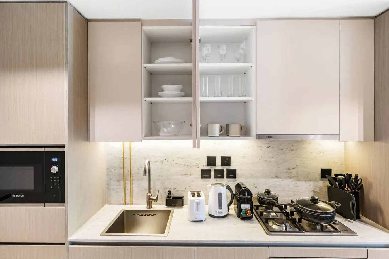 Una cocina moderna con gabinetes claros y una estufa sobre la encimera.
