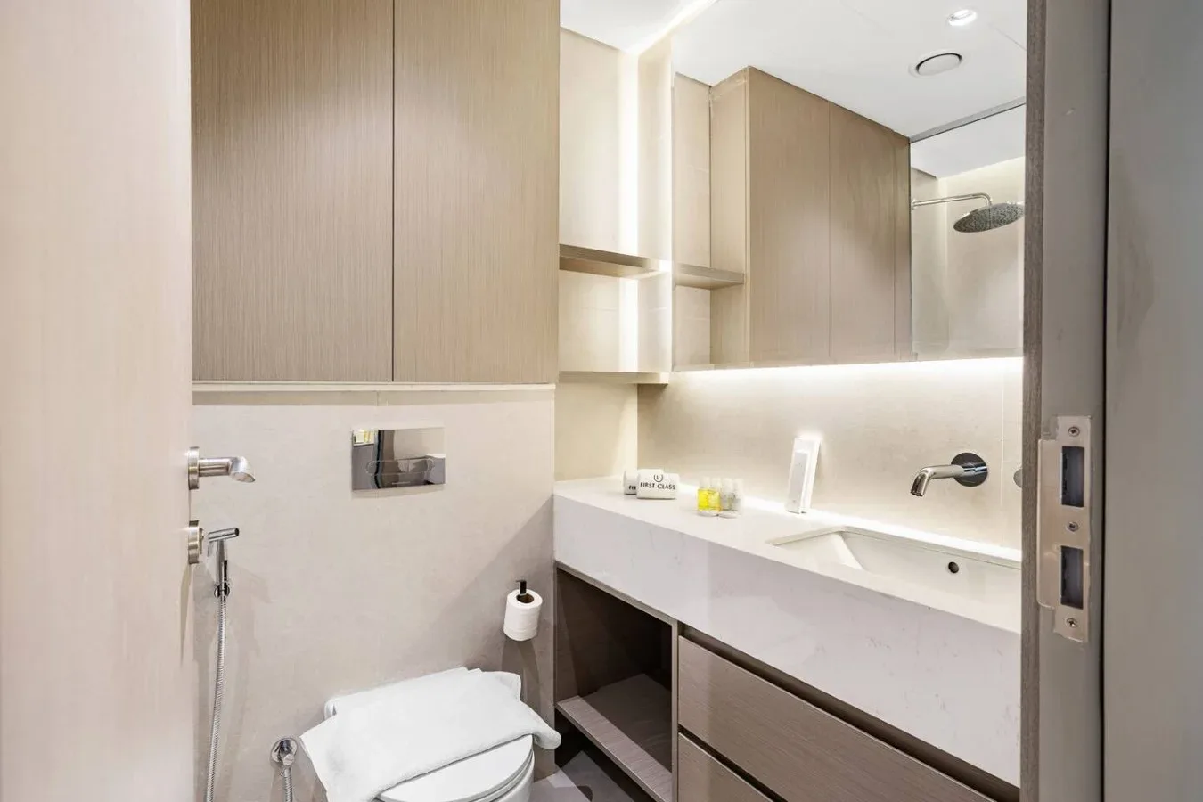 Un baño con una encimera de lavabo larga, espejo e inodoro.