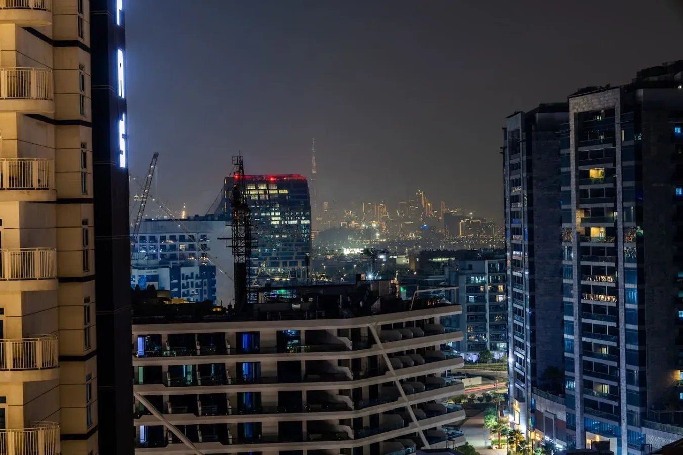 El horizonte de la ciudad brilla de noche entre edificios altos.