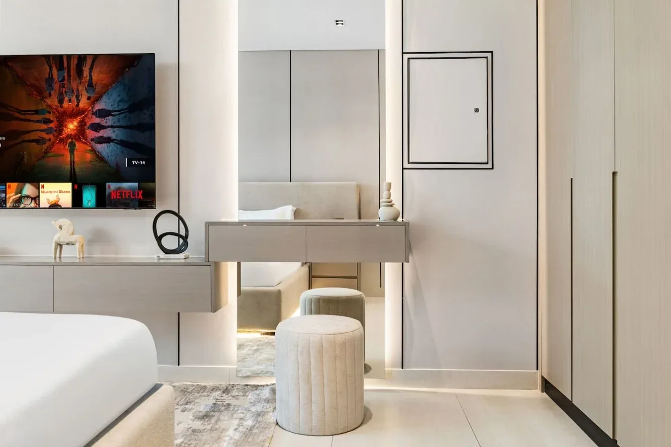 Dormitorio con una cama, un televisor de pared y un tocador.