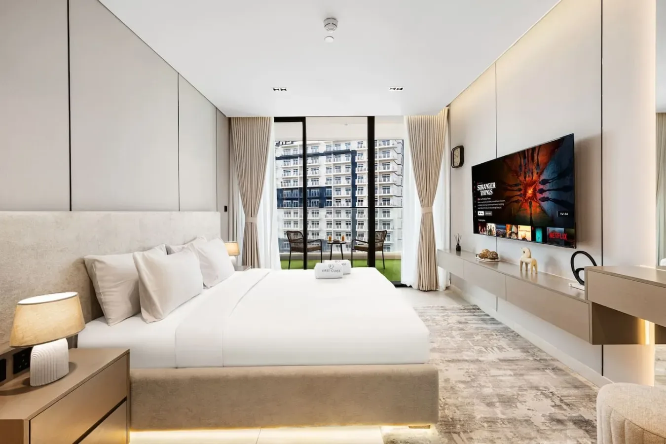Un dormitorio luminoso con una cama grande y ventanas de suelo a techo.