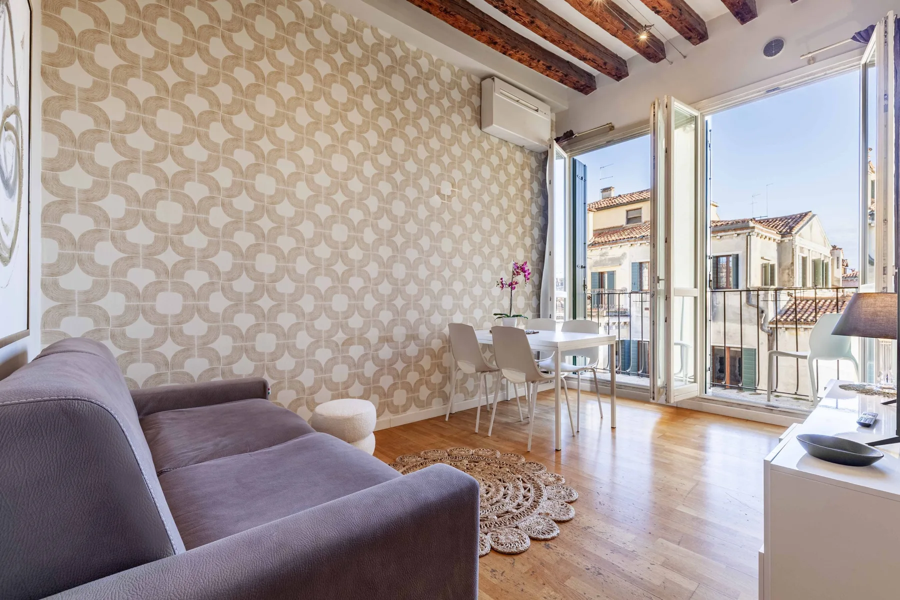 A bright living and dining area opens onto a balcony through glass doors.