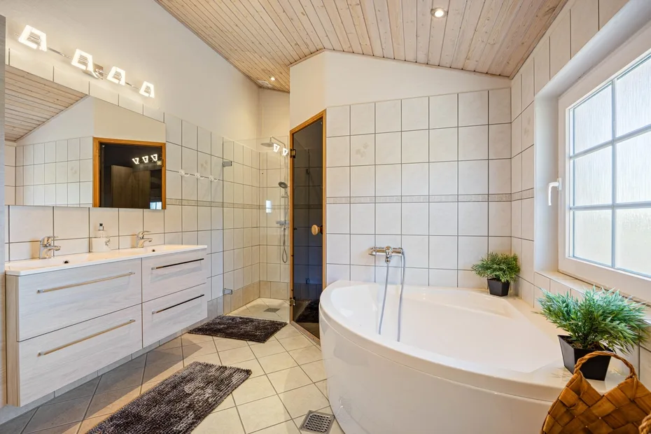 Un baño luminoso con azulejos cuenta con bañera, lavabo y ventana.