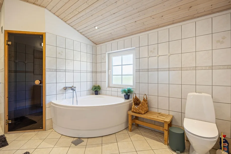 Un baño de azulejos con bañera, ducha y ventana.