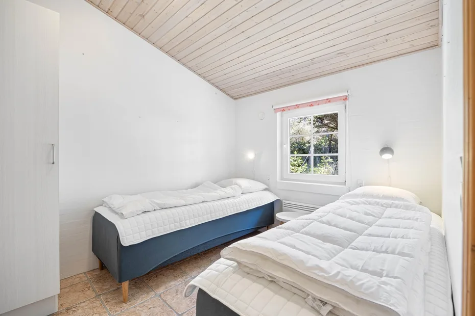 Un dormitorio luminoso con dos camas y una ventana.