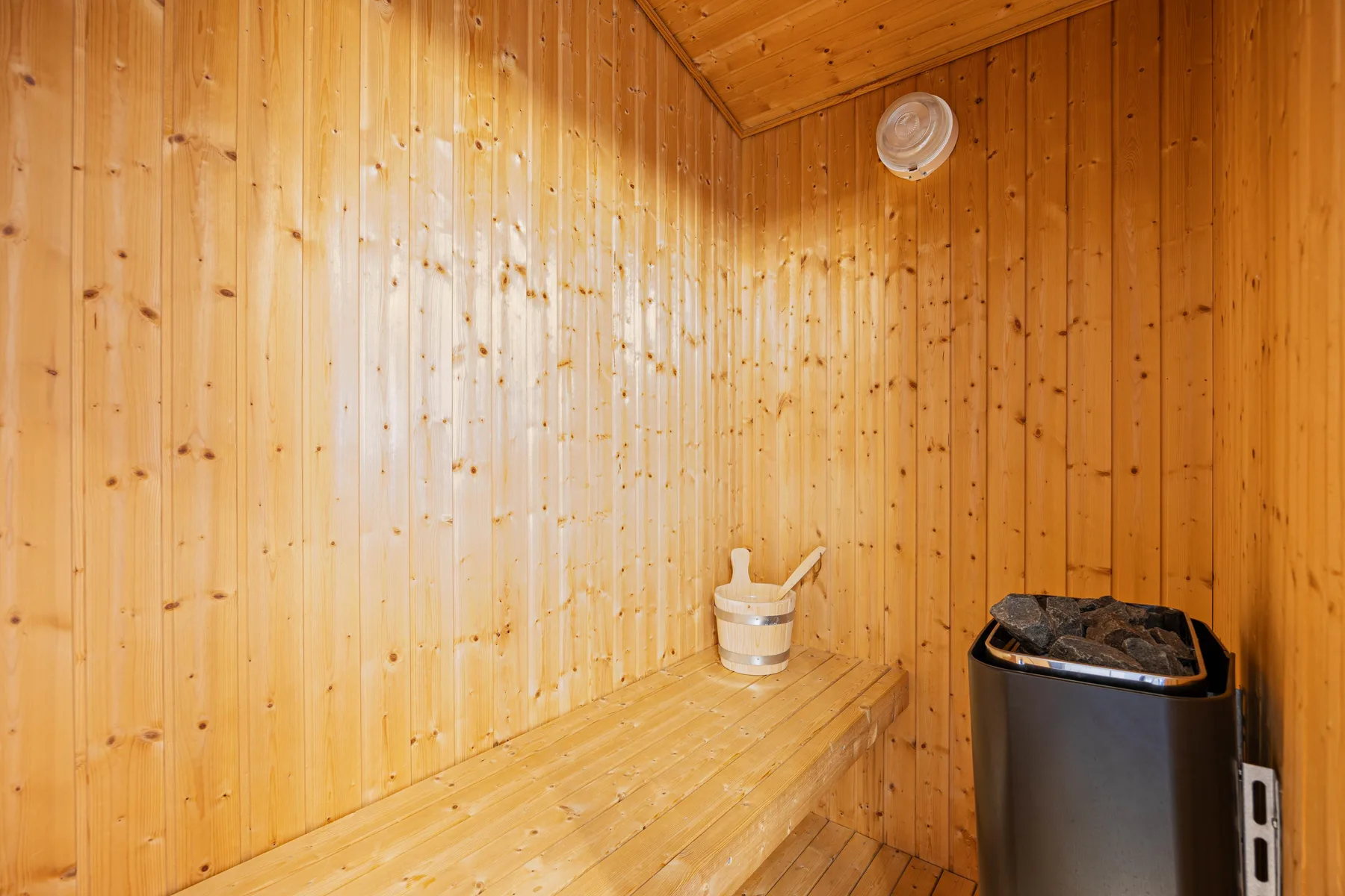 Una sauna revestida de madera con un banco y una estufa.