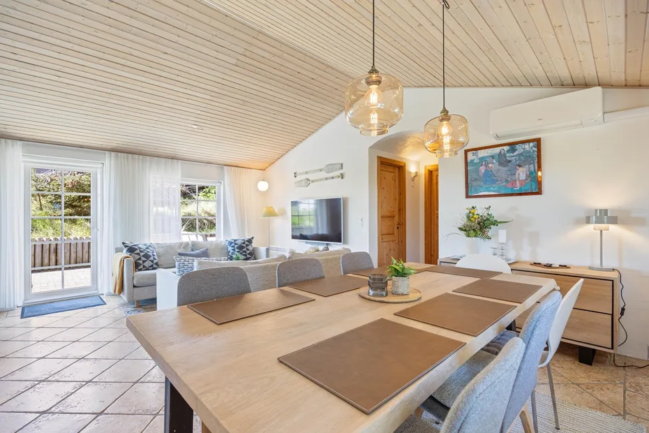 Comedor con una mesa larga y asientos, junto a una sala de estar.