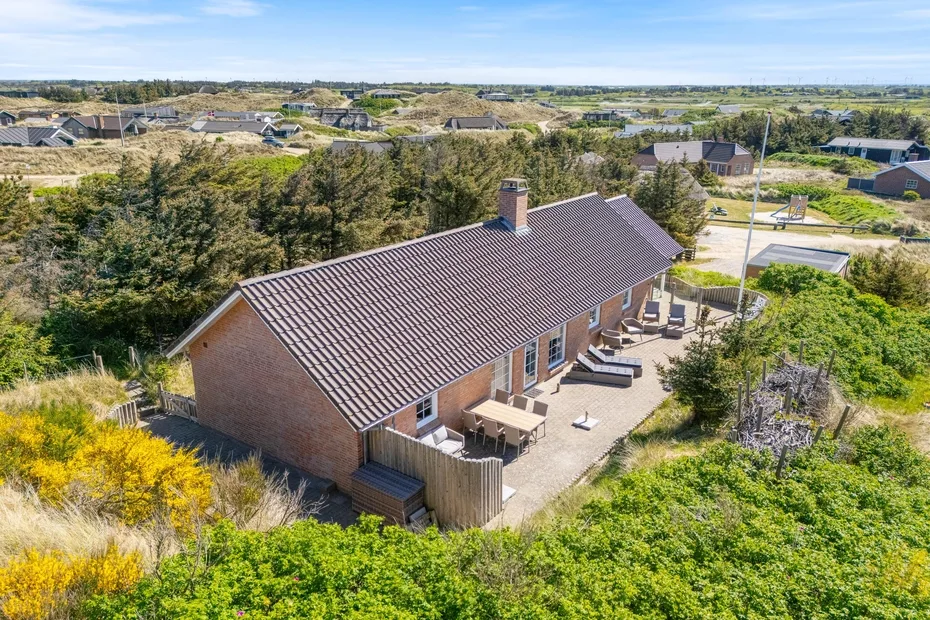 Vista aérea de una casa con patio pavimentado rodeada de vegetación.