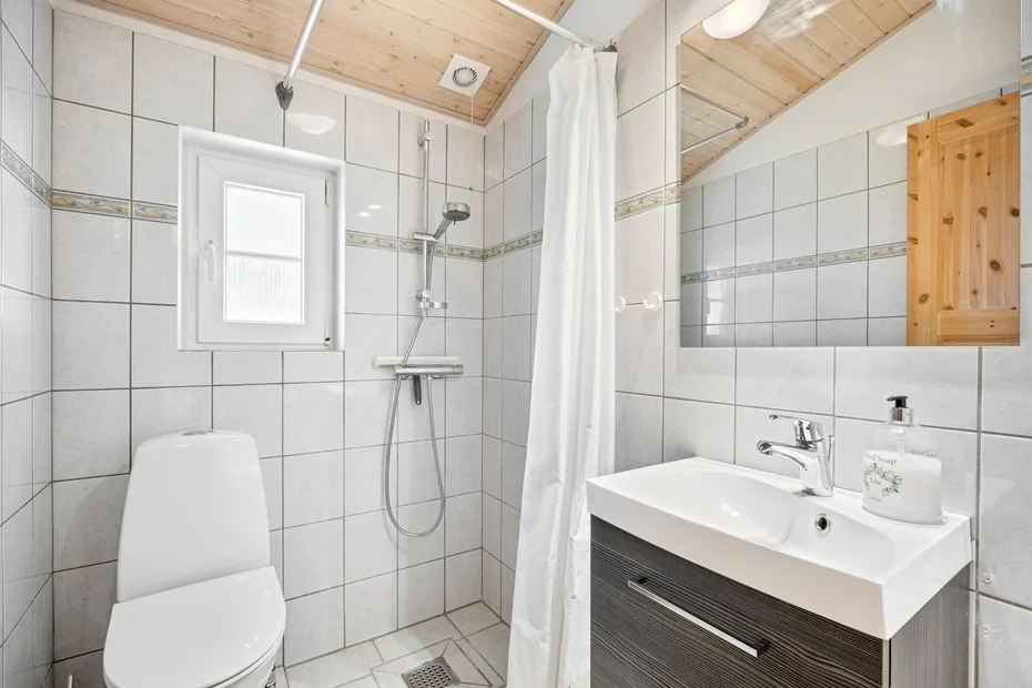 Un baño con azulejos, ducha, inodoro y lavabo.