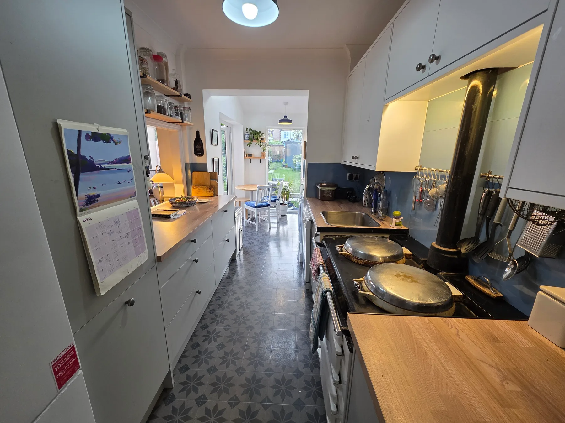Una cocina estrecha con encimeras, una placa de cocina y un comedor al fondo.