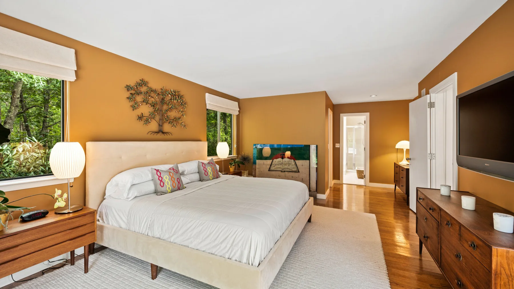 Un dormitorio con una cama grande, paredes de tonos cálidos y un televisor.