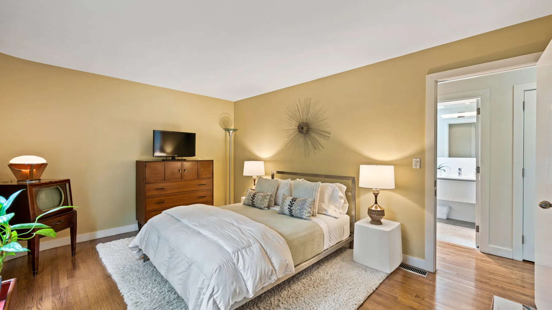 Un dormitorio con una cama bien hecha, mesitas de noche y una cómoda de madera.