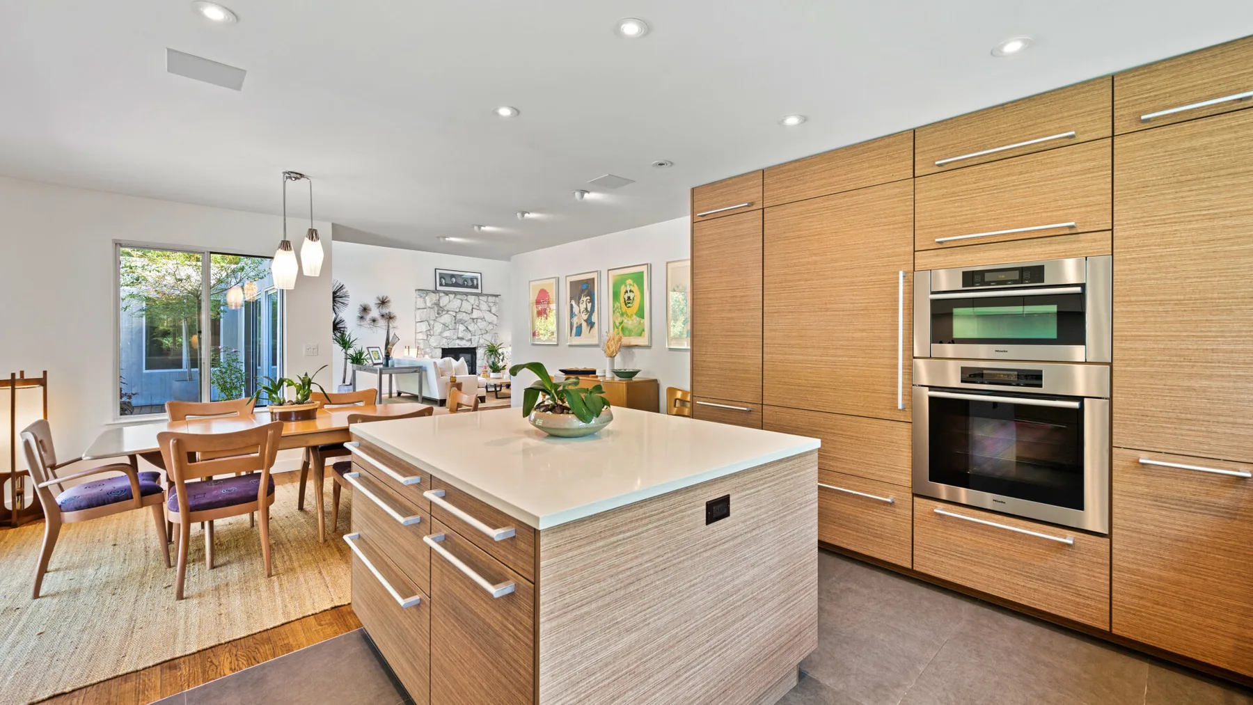 Una cocina luminosa con una gran isla y una mesa de comedor junto a las ventanas.