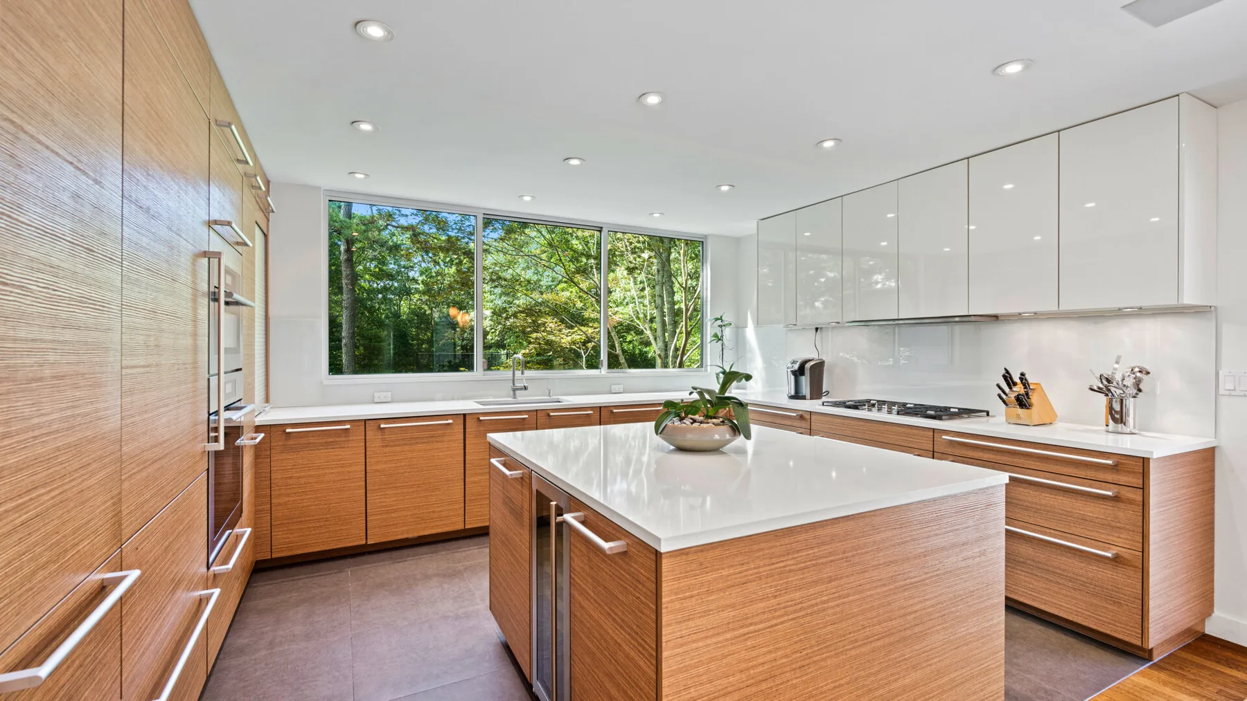 Una cocina luminosa con gabinetes de madera, encimeras blancas e isla central.