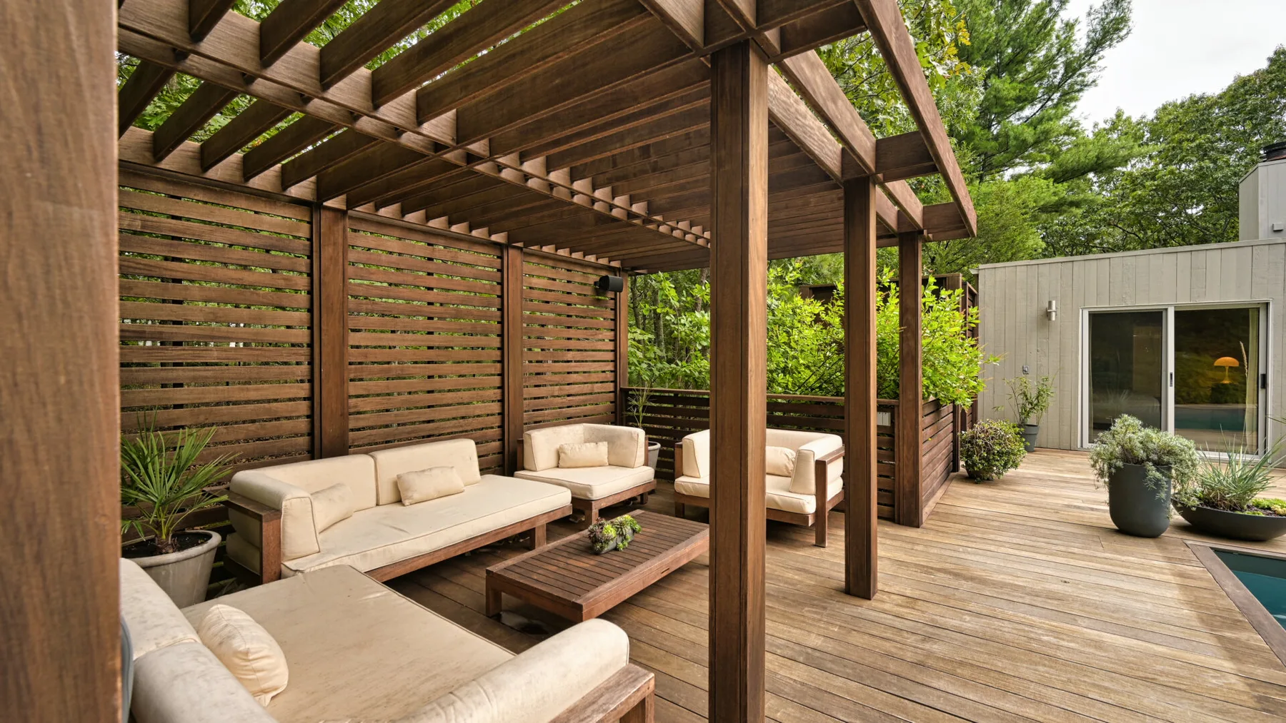 Zona exterior cubierta con asientos, suelo de madera y una mesa baja.
