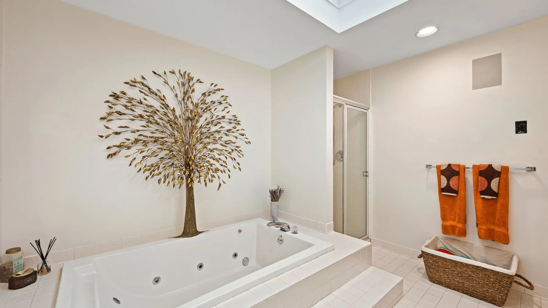 Un baño luminoso con una bañera empotrada y un árbol decorativo en la pared.