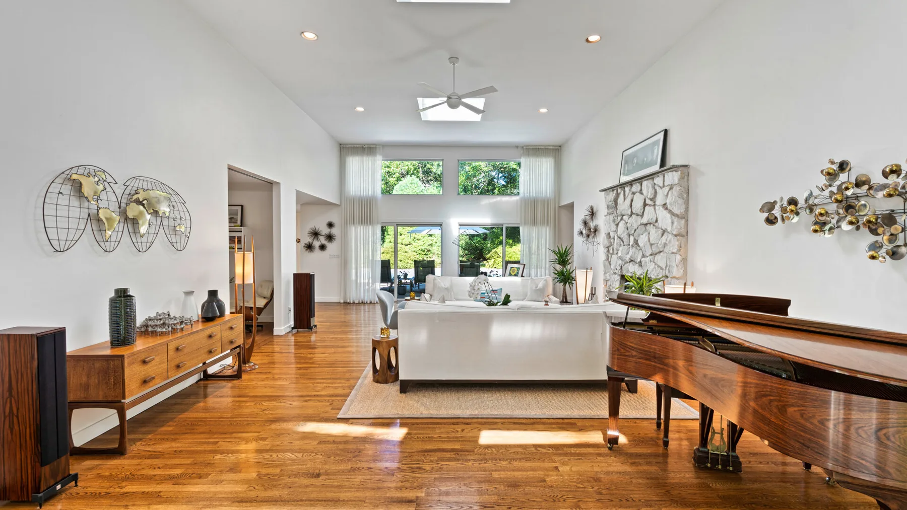 A bright living room with a white seating area and a grand piano.