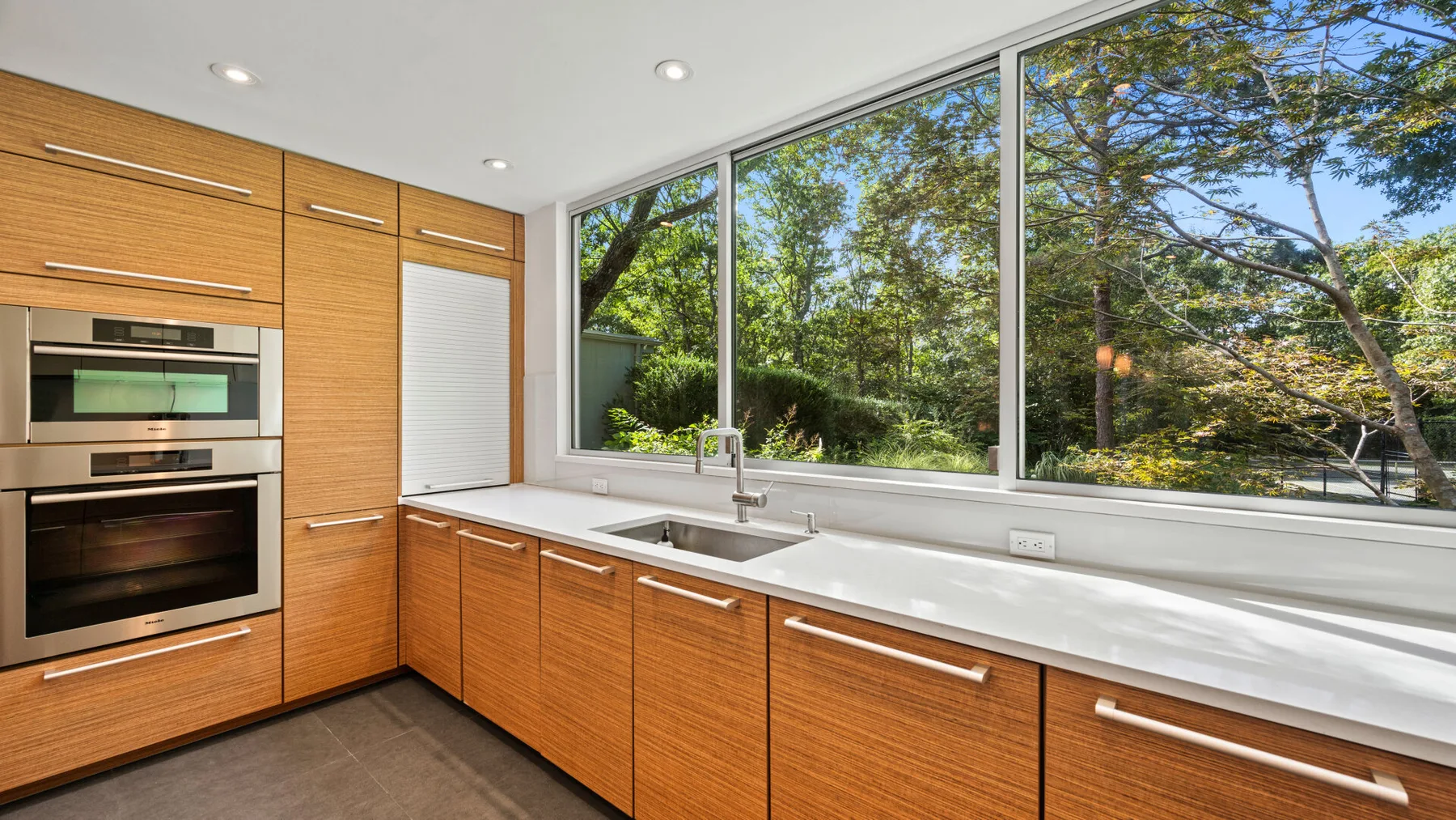 Una cocina moderna con gabinetes de madera y una amplia ventana con vistas a la vegetación.