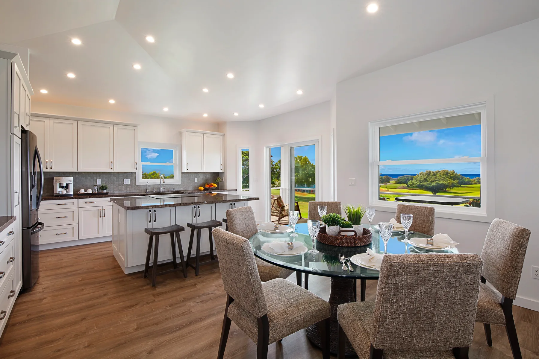 A bright kitchen and dining area with an island, table, and large windows.