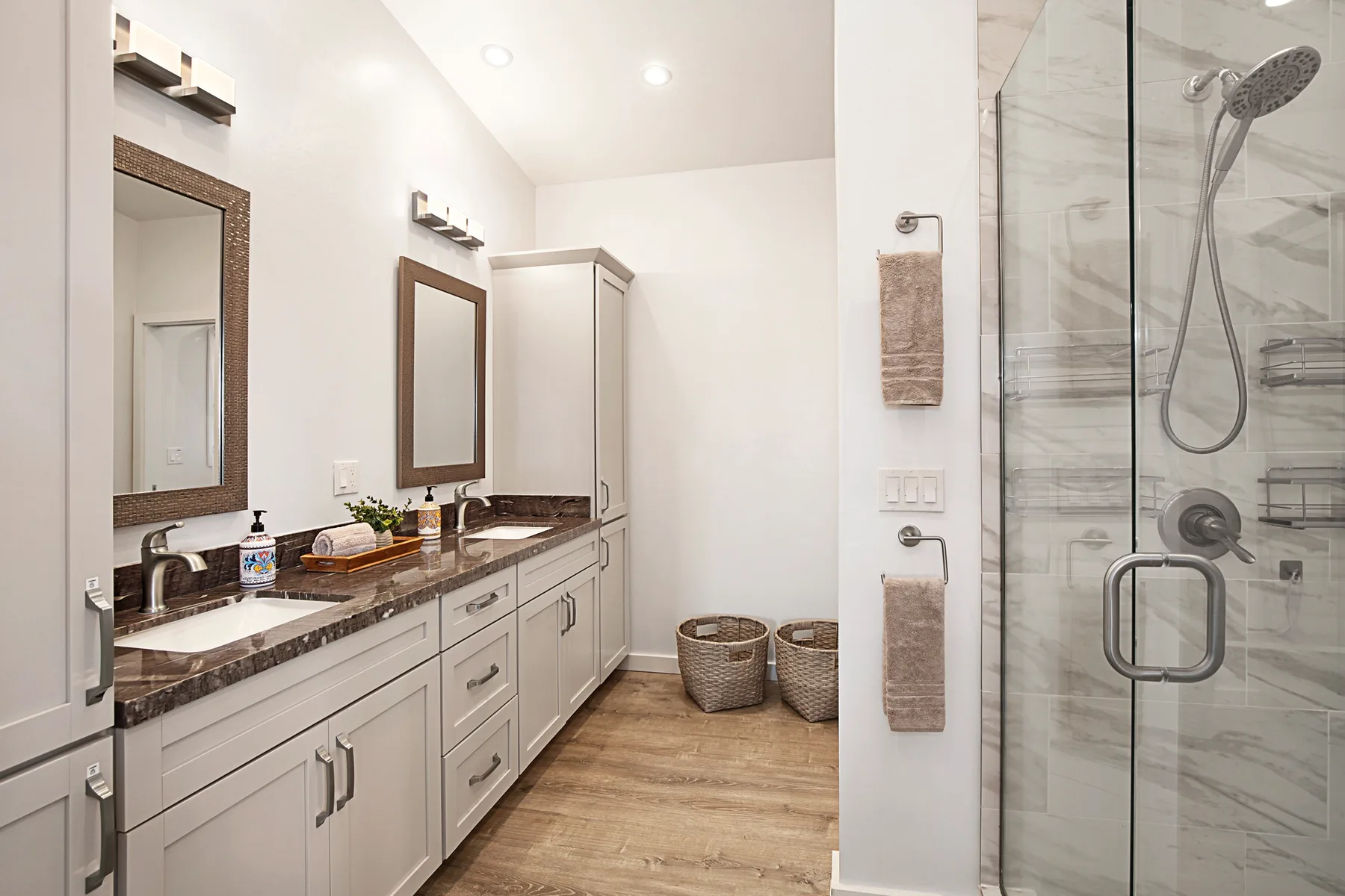 A bright bathroom with a long vanity and a glass-enclosed shower.